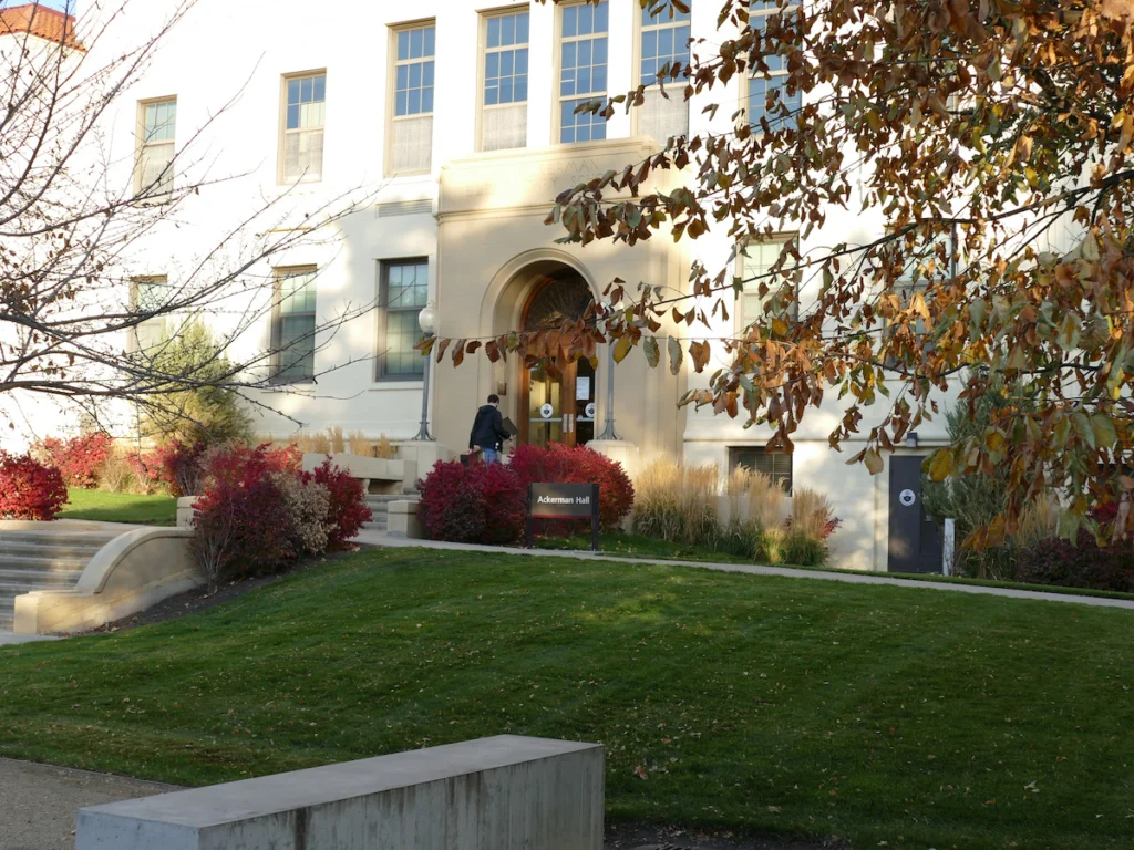 A student walks in the front door of Ackerman Hall, home of the College of Arts, Humanities and Social Sciences