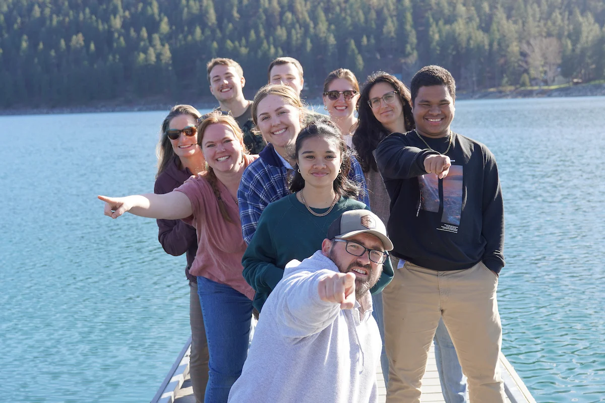 Dr. Daniel Costie and students stand on a pier and point at the camera during the Rural Planning Program, 2024