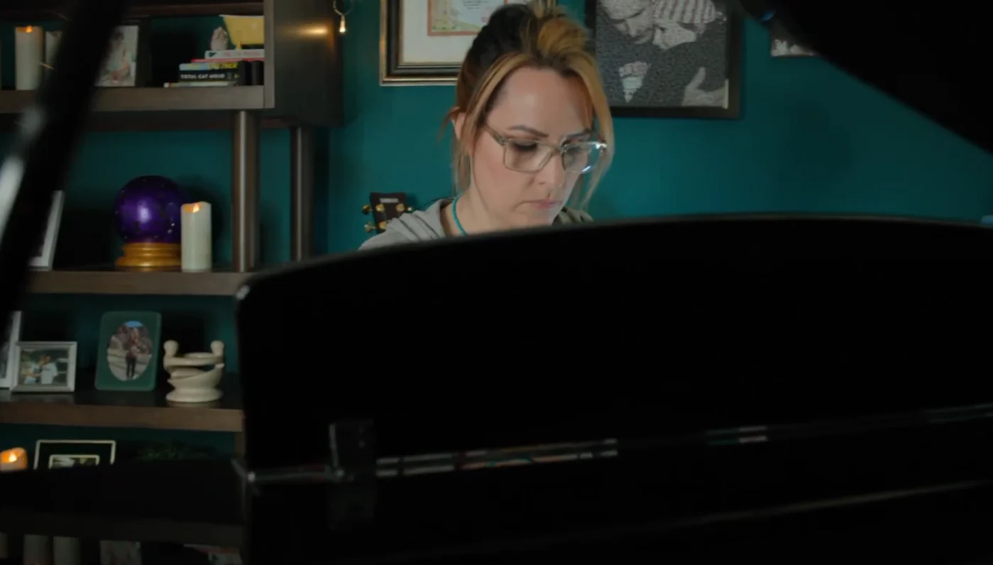 Lisa MacPherson sitting playing piano in a screengrab from this feature video