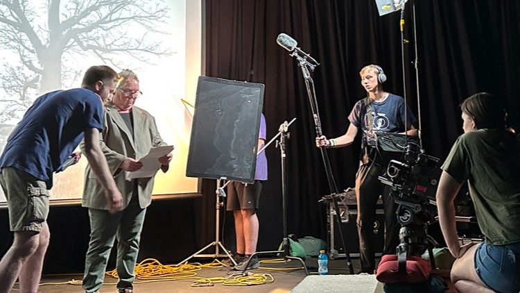 Film studies Minor students filming a scene on set. Cameras, lights microphones all visible. 