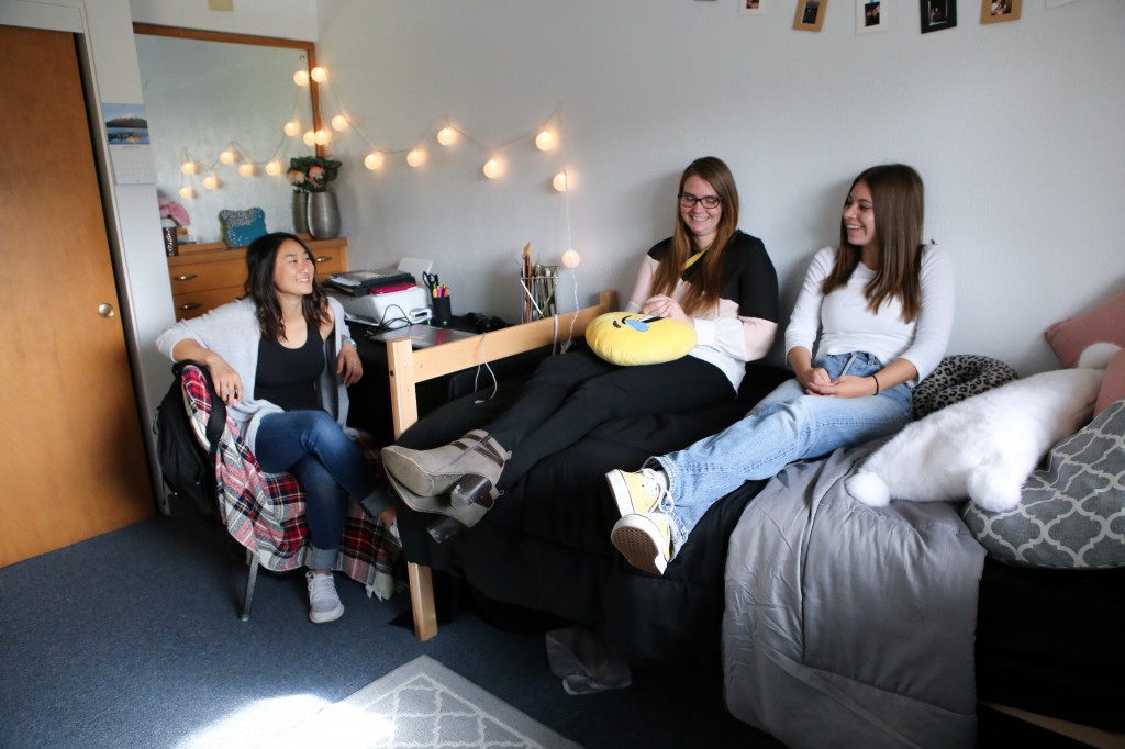 Three students sitting in a different Eocene bedroom smiling and talking