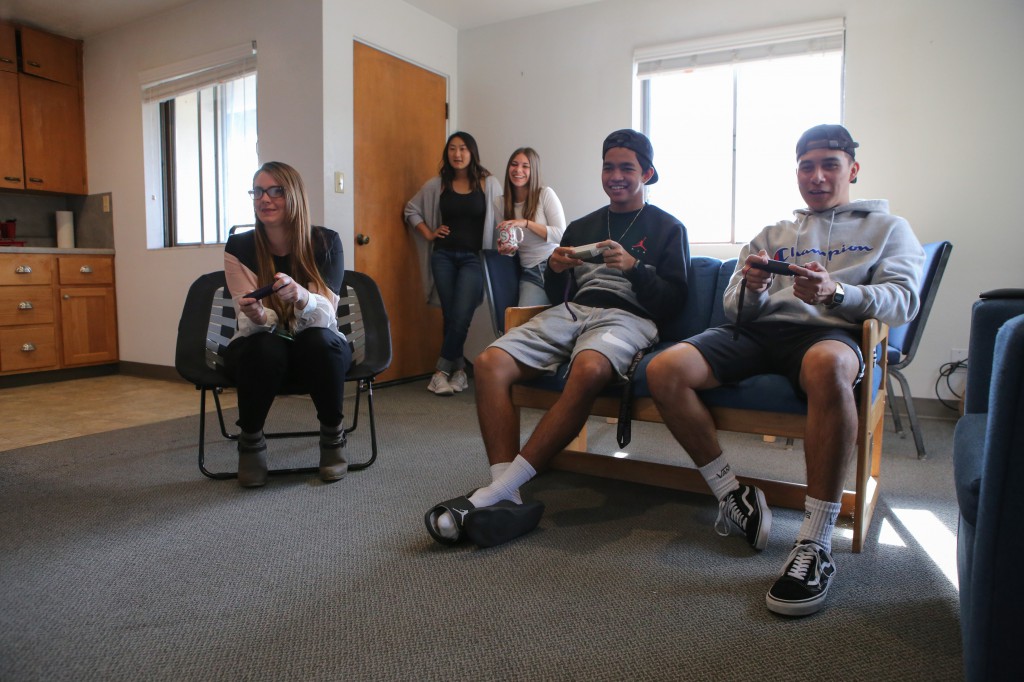 A group of five students sitting in an Eocene suite living room playing a game on an unseen TV