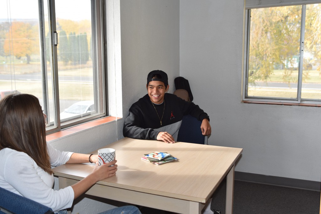 Two students sitting at tables across from each other talking in an Eocene suite living room