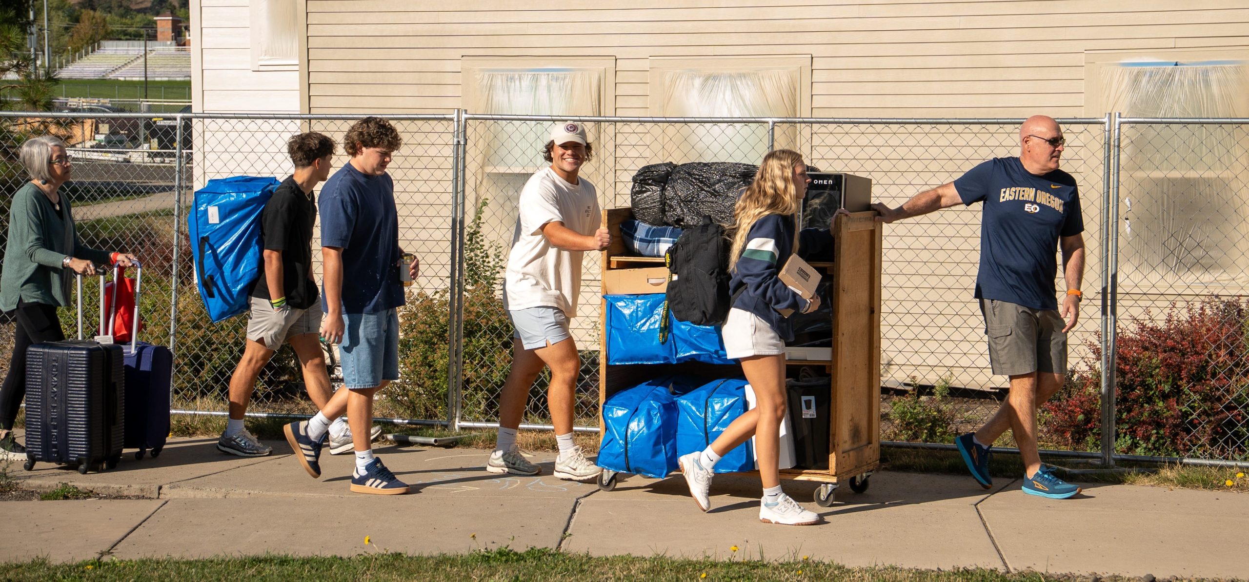 Photo by Matt Peterson. 

Photo of family and students moving into North Hall. Pushing cart with belongings. 