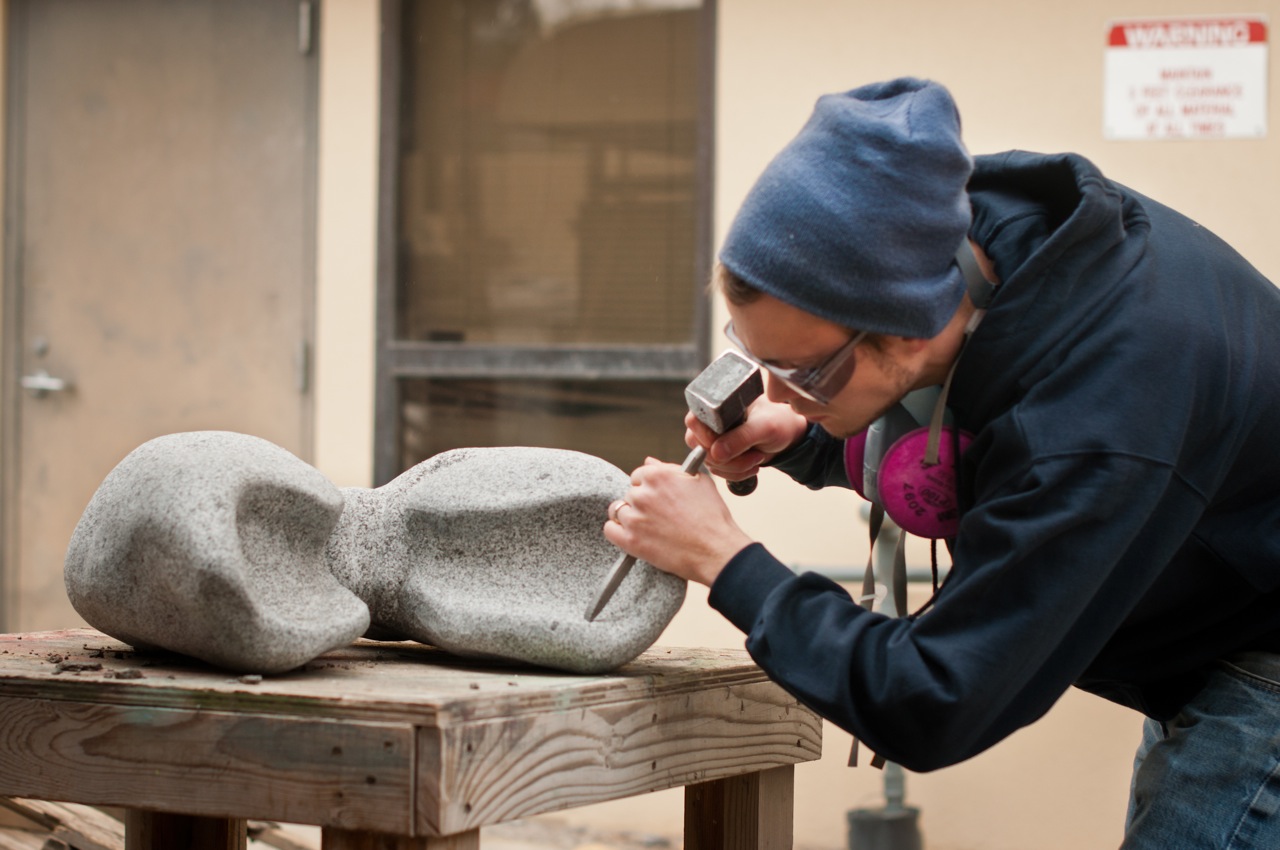EOU Art student working on a rock carving in studio