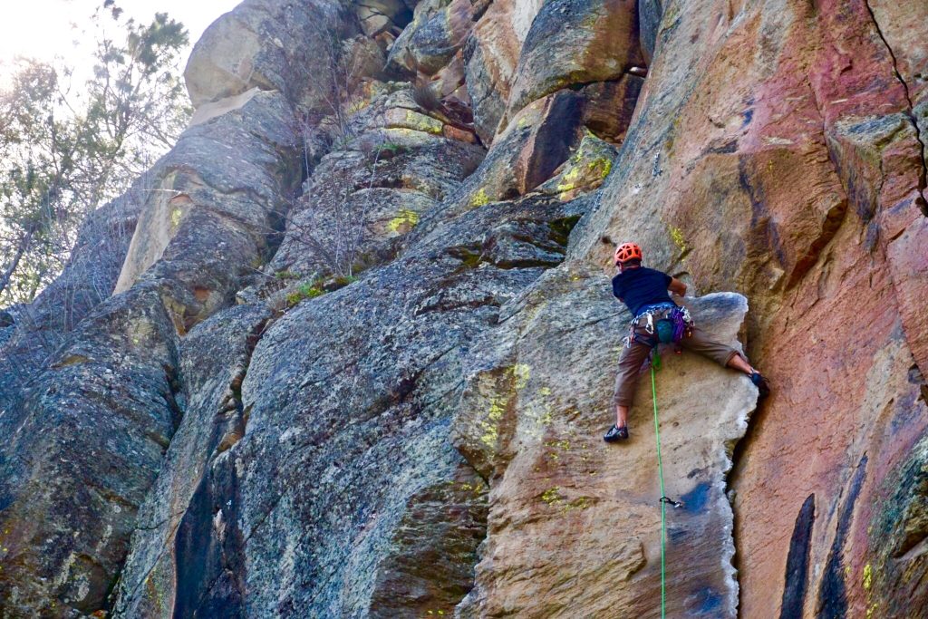 Rock climber scales a technical route at a local crag on the OUT 180 Lead Rock Climbing course. 