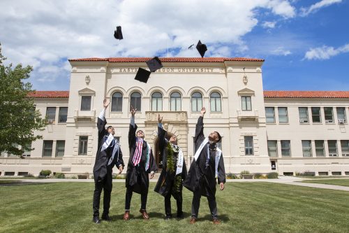 Graduates throw their caps in front of inlow hall
