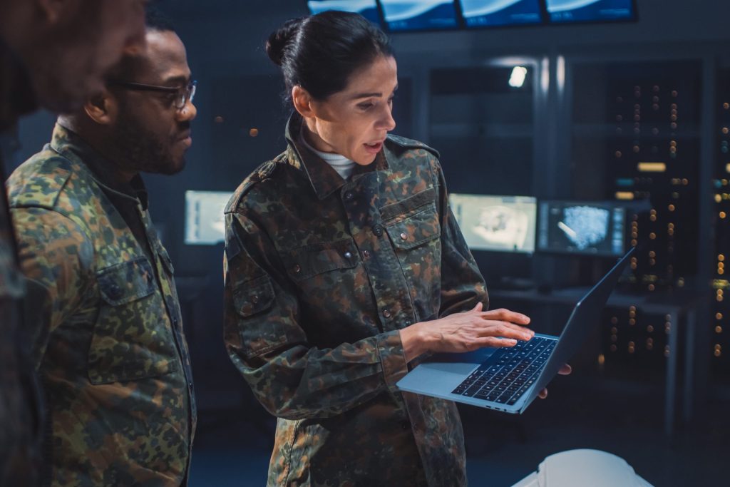 International Team of Military Personnel Have Meeting in Top Secret Facility, Female Leader Holds Laptop Computer Talks with Male Specialist. People in Uniform on Strategic Army Meeting