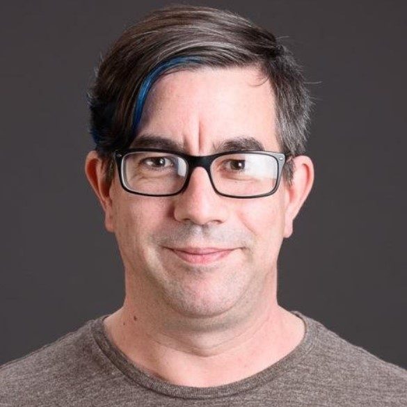 Male with dark short hair wearing glasses and a brown shirt.