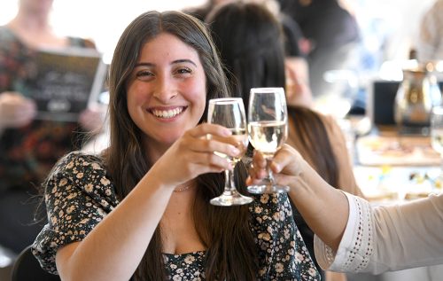 A woman smiling and toasting at the scholarship celebration