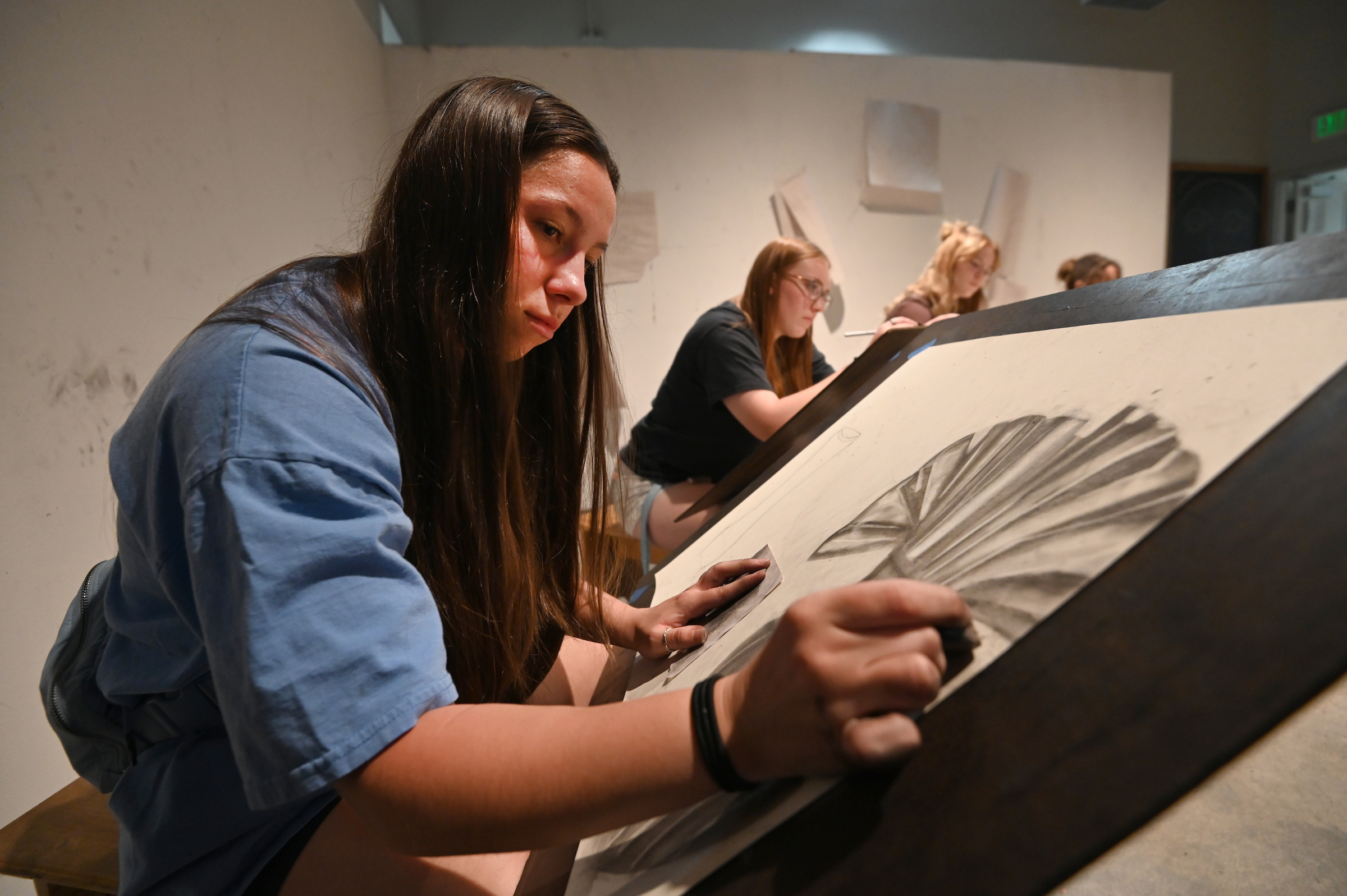 EOU student working on a charcoal drawing in class