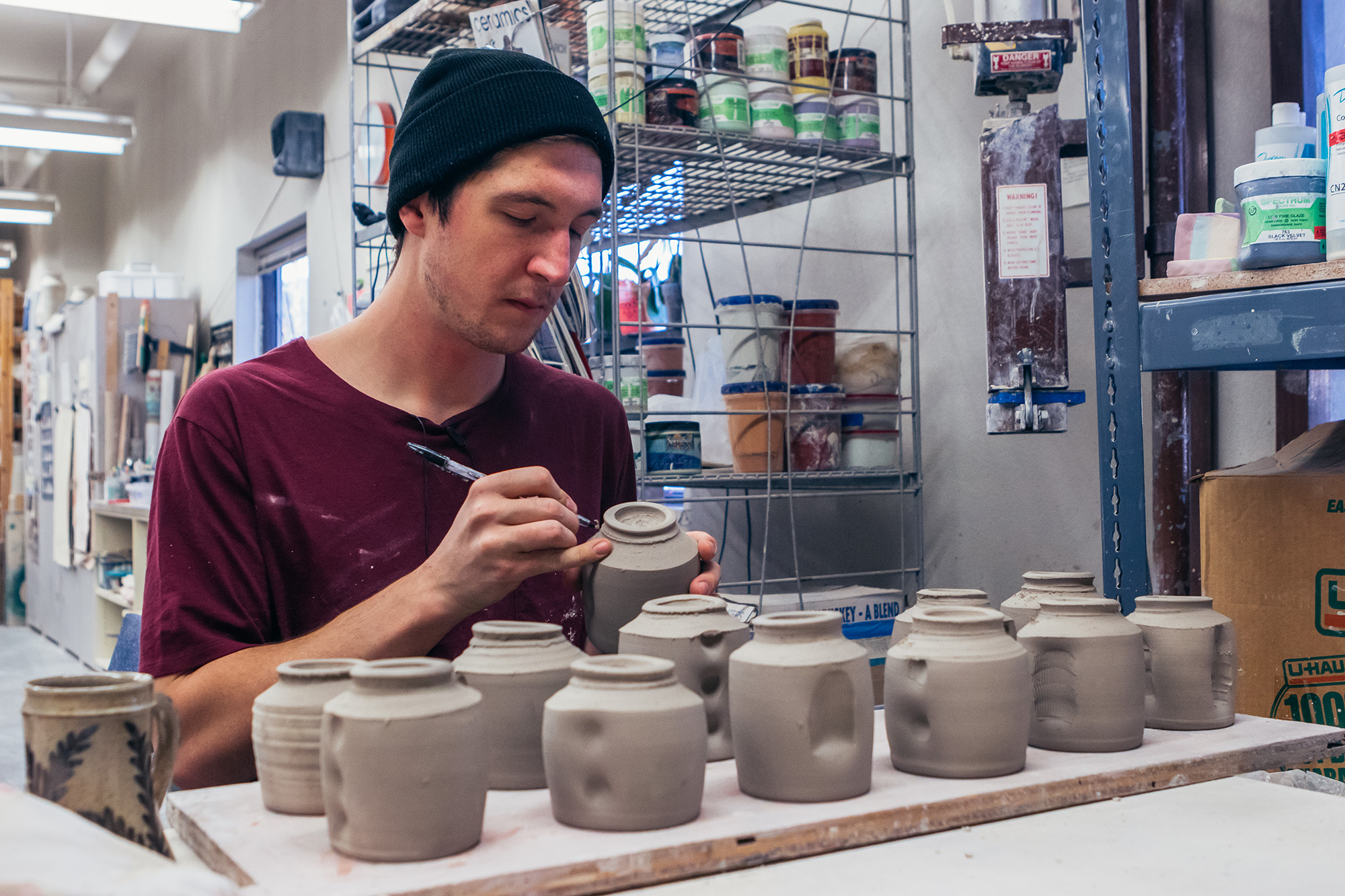 An EOU Art Student working on a set of ceramic jars in-studio